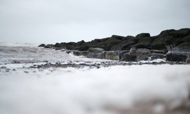 Soğuk bir kış gününde güzel, sakin bir deniz suyu. Deniz seviyesinin yükselmesi ve küresel ısınma nedeniyle dev taşlar deniz savunma altyapısı olarak yerleştirildi. Dağ zeminli çakıl taşı plajı.