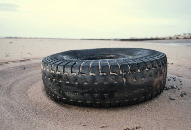 Lastik kirli eski araç lastiği kumlu, lüks bir plaj istikametinde kıyıya vurmuş. Çevresel plastik kirliliği sorunu dünya haberlerine neden oluyor. Plajlarda sağlık felaketi.                            