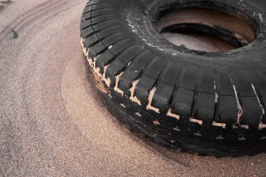 Lastik kirli eski araç lastiği kumlu, lüks bir plaj istikametinde kıyıya vurmuş. Çevresel plastik kirliliği sorunu dünya haberlerine neden oluyor. Plajlarda sağlık felaketi.                            
