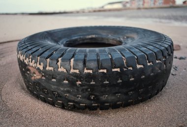 Lastik kirli eski araç lastiği kumlu, lüks bir plaj istikametinde kıyıya vurmuş. Çevresel plastik kirliliği sorunu dünya haberlerine neden oluyor. Plajlarda sağlık felaketi.                            