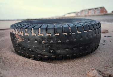 Lastik kirli eski araç lastiği kumlu, lüks bir plaj istikametinde kıyıya vurmuş. Çevresel plastik kirliliği sorunu dünya haberlerine neden oluyor. Plajlarda sağlık felaketi.                            