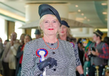 Morecambe, İngiltere, 05 / 05 / 2017, Eski tarz güzel bir saç stili ve giysisi olan bir kadın, Rosette rozeti olan, şık giyinen ve kostüm giyip poz veren moda kadınları.