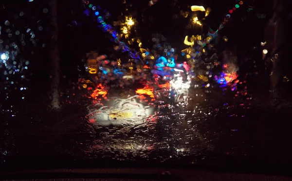 摘要断断续续的雨滴落在车窗上 背景中城市和街道灯火通明 又累又醉在潮湿又潮湿的条件下开车 安全驾驶 — 图库照片