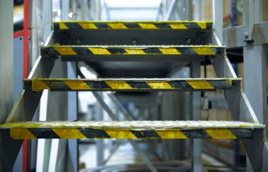 Londra, İngiltere, 05 / 05 / 2018 Kentsel bir fabrika ortamında endüstriyel metal bir merdiven. Gelecek vaad eden bir kıyamet ortamı. Sağlık ve güvenlik için sarı bant kayma ve düşme riski. 