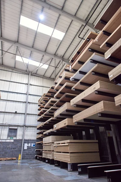 A large industrial racking in a woodworking diy factory,  holding and storing various wooden laminate plywood chipboard boards. wood work carpentry and diy unsustainable building materials.