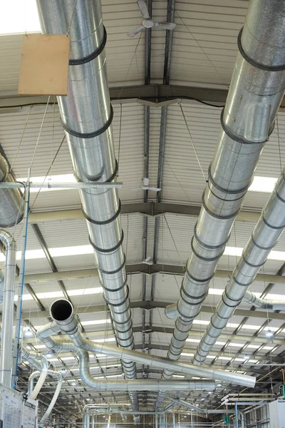 Industrial metal air flow and air conditioning pipes on the ceiling of an industrial factory. keeping the air fresh and clean for health and safety purposes. Healthy clean working environment for workers rights.