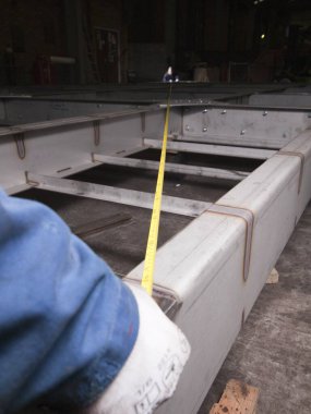 Londra, İngiltere, 05 / 05 / 2018 Bir mezura mühendisi yeni kaynaklanmış metal bir objeyi incelemek ve ölçmek için mezura kullanıyor. mekanik parçalarla hassas ölçüm gereklidir.