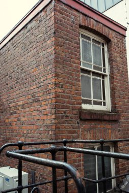 Katı kırmızı, eski, sert bir tuğla duvar. Pahalı, yıpranmış dış duvar kalitesi olan sağlam, eski bir yapı. Kırmızı tuğlalar tekrar tekrar diziliyor. tuğla katmanları