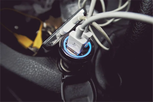 A usb car 12 volt usb cigarette lighter charging port in the interior of a messy car. Charging phone and digital electronic equipment on the move with alternator. 12 volt convertor usb travel socket.