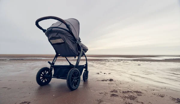 Blackpool, İngiltere, 05 / 05 / 2019 bir bebek bebek bebek puseti bebek arabası engin bir plaj manzarasında şafakta ve alacakaranlıkta. Rahatlamak ve çocuklarla tatile çıkmak. Aileyle açık havada kaynaşmak..