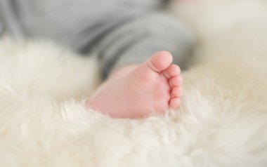 Sığ bir tarlada çekilmiş güzel, yumuşak, narin, genç bir bebek ayağı. Sakin renkler ve hisset. Bebek bakımı ve refah. Bebek ayakları krem bir halıda.