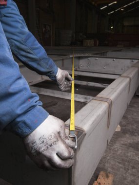 Londra, İngiltere, 05 / 05 / 2018 Bir mezura mühendisi yeni kaynaklanmış metal bir objeyi incelemek ve ölçmek için mezura kullanıyor. mekanik parçalarla hassas ölçüm gereklidir.