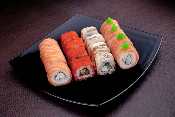 Siyah plaka üzerinde farklı suşi maki kümesi. Japon yemekleri üzerinde arka izole