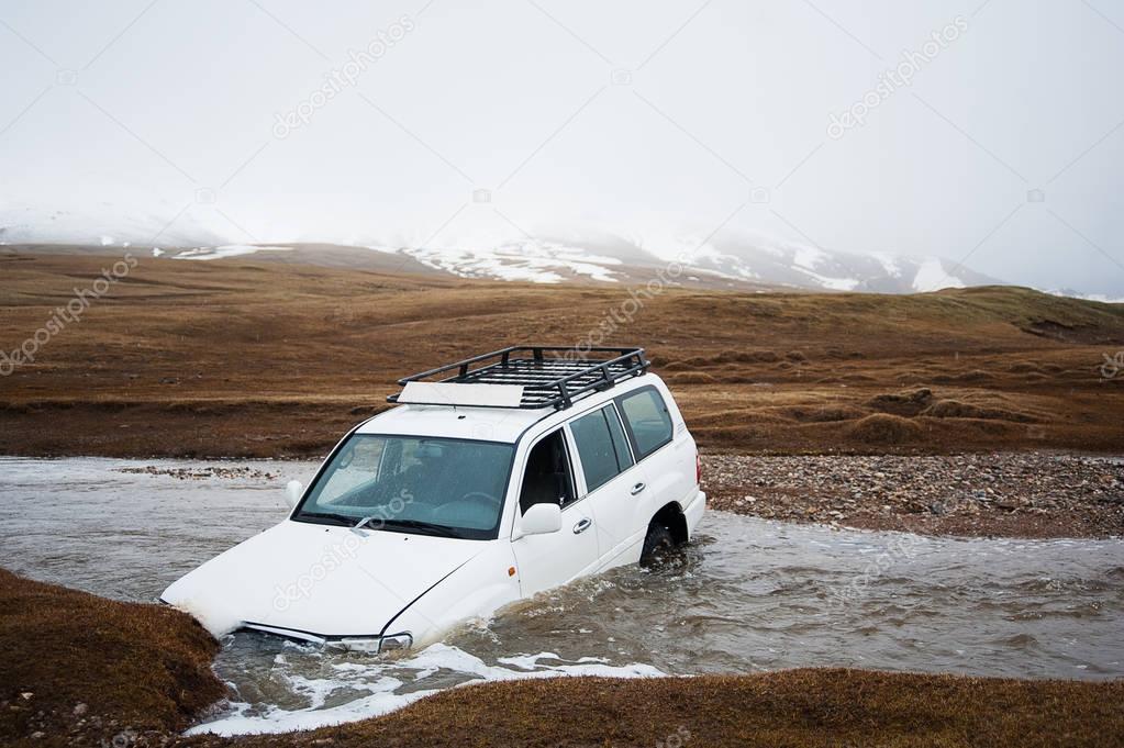 Accident on the road, car crash. Off-road expedition. Jeep 4x4 stuck in mountain river stream. The car drowned in the river. Extreme dangerous journey. Adventures in transit
