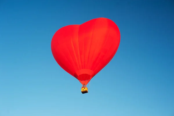 Червона повітряна куля у формі серця у чистому блакитному небі. Аеростат над польовим пейзажем. крупним планом — стокове фото