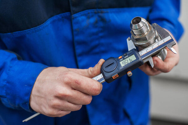 Close-up of the hand of a worker measuring a part from the mechanism of an accurate measuring instrument. Electronic caliper