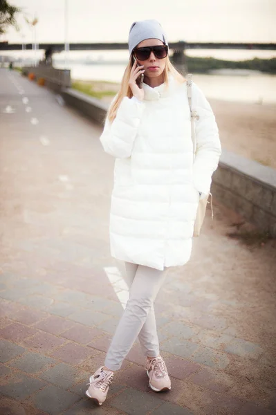 时尚酷笑的女孩在街上的白色衣服上谈论智能手机 — 图库照片
