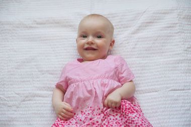 Pembe elbiseli kız şirin bebek beyaz adam yatıyor. Yakın çekim portre, gülen bebek