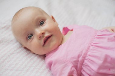 Pembe elbiseli kız şirin bebek beyaz adam yatıyor. Yakın çekim portre, gülen bebek