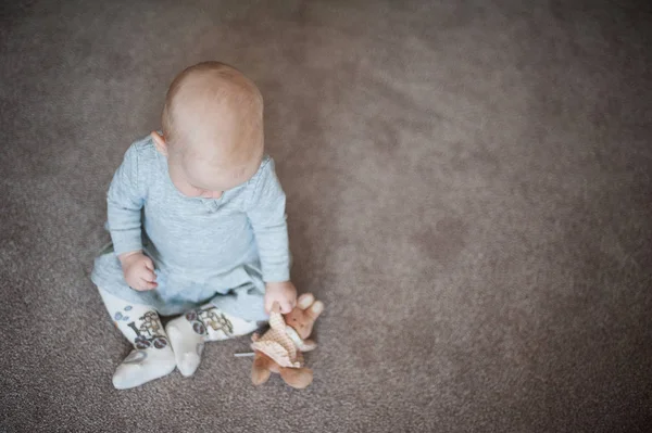 Linda niña triste con conejito en la mano. Primer plano retrato de niña con juguete en vestido gris . — Foto de Stock