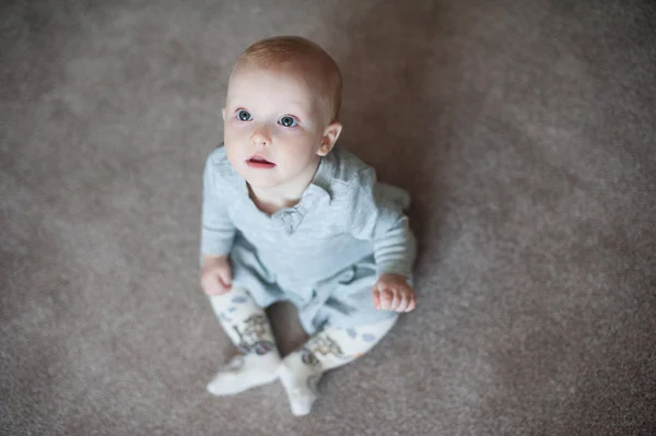 Roztomilý funny baby girl laughting a podíváte se na kameru. Zblízka portrétní holčička v šedé šaty — Stock fotografie