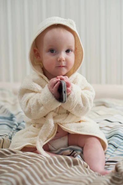 Bébé drôle mignon en peignoir avec téléphone dans ses mains — Photo