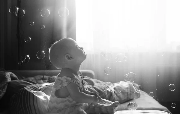 Divertente carina bambina guarda bolle di sapone nella stanza. Filtro instagram tono bianco e nero di sfondo. Concetto infanzia felice . — Foto Stock