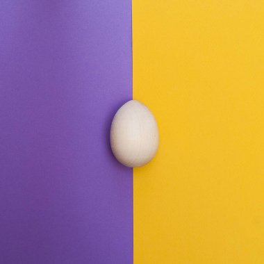 Mutlu Paskalya kavramı. Düz yatıyordu. En az dikey kavramı. Üstten Görünüm. Sarı mor zemin üzerine ahşap yumurta.