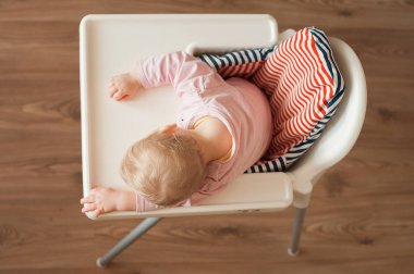 Yorgun çocuk sandalyesi öğle yemeğinden sonra uyuyor. Şirin Bebek girllying tablo tepsi yüzünde. Üstten Görünüm