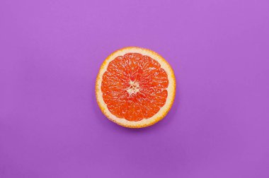 En az tarzı, yaratıcı düzen portakal ve greyfurt. Düz yatıyordu. Gıda kavramı. Mor zemin üzerine yarım portakal.