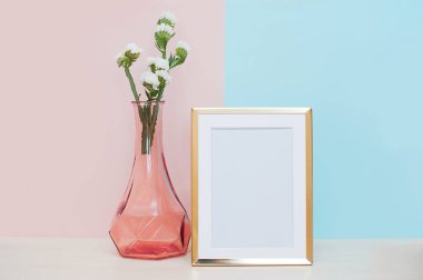 Tablo üzerinde pembe aranjman beyaz çiçekli pembe mavi arka plan boş modern altın beyaz fotoğraf çerçevelemek. Ev dekorasyon. Moke kadar 