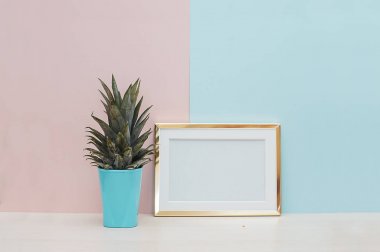 Modern ev dekorasyonu ile altın boş fotoğraf çerçevesi ve tropikal bitki pembe mavi zemin üzerine kadar alay