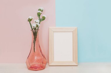 Modern ev dekorasyonu ahşap boş fotoğraf çerçevesi, vazo ve tropikal bitki pembe mavi zemin üzerine sahte