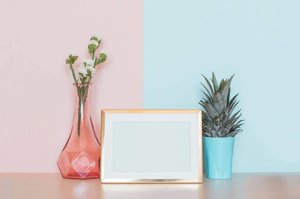 Moderna decoración del hogar maqueta con marco de fotos en blanco de oro, jarrón y planta tropical sobre fondo azul rosado — Foto de Stock