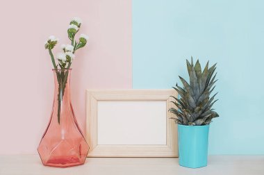 Modern ev dekorasyonu ahşap boş fotoğraf çerçevesi, vazo ve tropikal bitki pembe mavi zemin üzerine sahte