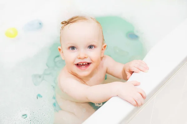 可爱的小女孩在浴室的快乐。微笑的孩子玩泡沫和鸭子 — 图库照片