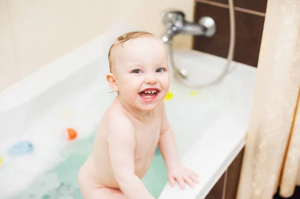 Feliz bonito bebê menina no banheiro. Criança sorridente brincando com espuma e pato — Fotografia de Stock