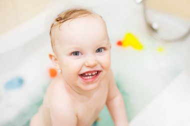 Banyoda kız mutlu sevimli bebek. Köpük ve ördek ile oynayan gülümseyen çocuk