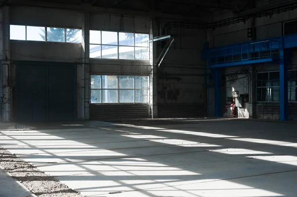 Fábrica de fabricación. Edificio del hangar vacío. Fondo tonificado azul. La sala de producción con grandes ventanales y estructuras metálicas — Foto de Stock