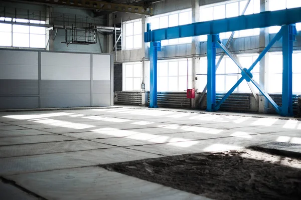 Manufacturing factory. Empty hangar building. Blue toned background. The production room with large windows and metal structures