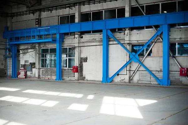 Manufacturing factory. Empty hangar building. Blue toned background. The production room with large windows and metal structures