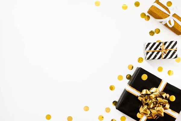 Рождественская квартира. Рождественские подарки, черно-золотая оберточная бумага на белом фоне с золотыми конфетти — стоковое фото