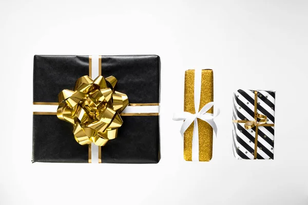 Рождественская композиция Рождественские подарки, черно-золотая оберточная бумага на белом фоне — стоковое фото