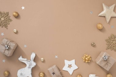 Noel kompozisyonu. Pastel bej arka planda hediyeler, zanaat ve altın madalyalarla çerçevelenmiş.. 