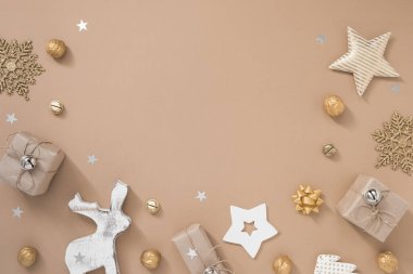 Noel kompozisyonu. Pastel bej arka planda hediyeler, zanaat ve altın madalyalarla çerçevelenmiş.. 
