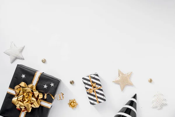 Подарочная коробка или коробка подарков, шляпы и звезды на белом столе. Рождественская композиция с черно-золотыми украшениями — стоковое фото