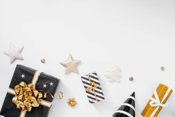 Стильное рождественское украшение. Подарки, шляпы, черно-золотые украшения на белом фоне — стоковое фото