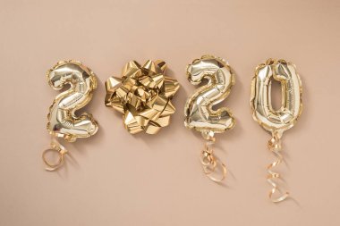 Mutlu yıllar 2020 kutlamaları. Altın folyo balonları 2020 numaralı pastel bej arka planda izole edilmiş.