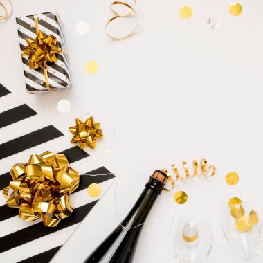Noel partisi kompozisyonu. Hediyeler, şapkalar, şampanya şişesi beyaz arka planda siyah ve altın süslemeler.. 