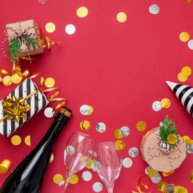 Noel partisi kompozisyonu. Hediyeler, şapkalar, şampanya şişesi kırmızı arka planda siyah ve altın süslemeler. 